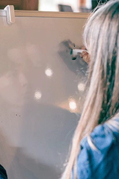 Frau schreibt auf ein Whiteboard von hinten